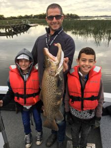 Team effort: Chris Farrugia, with his sons Charlie and Cooper and the 4.6 kg brown trout he caught from Lake Purrumbete on Friday morning (Picture: Lake Purrumbete Holiday Park).