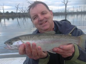 Anthony Forster of Fisheries Victoria with a feisty little rainbow trout from Lake Toolondo (Picture: Victorian Inland Charters).