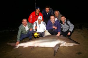 A shark after dark: Mick Kollaris (in red), Bill Athanasselis (in white with rod and reel), and the night shift from the Hotel Grand Pacific at Lorne, with the shark.